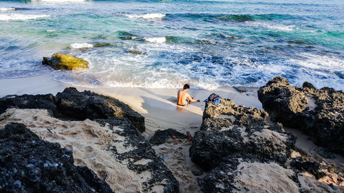 High angle view of man standing on rock by sea