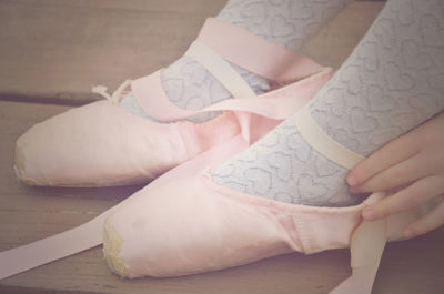 Low section of girl wearing ballet shoes