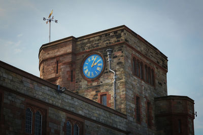 Low angle view of clock on building against sky