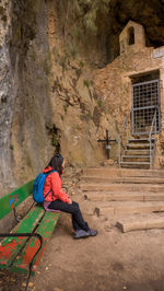 Rear view of man sitting on rock