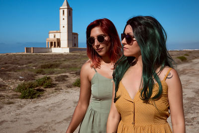 Young woman wearing sunglasses while standing on land against sky