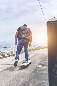 Rear view of man on railing against sky