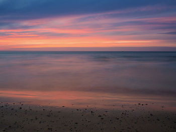 Scenic view of sea against dramatic sky during sunset