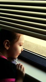 Close-up portrait of girl looking through window