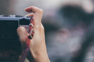 Cropped hand of person photographing with camera outdoors