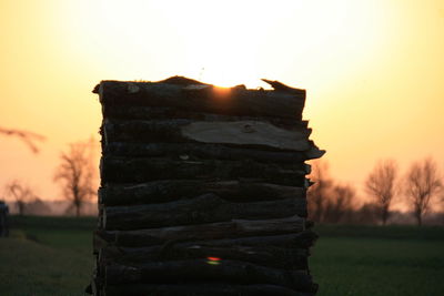 Close-up of stone stack on field against sky during sunset