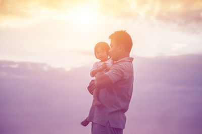 Rear view of mother and daughter standing against sky