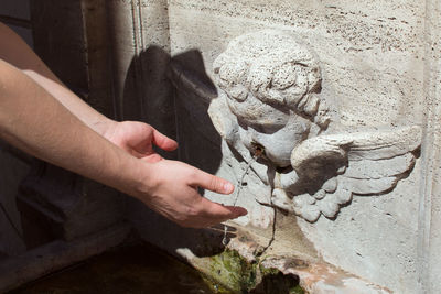 Close-up of hands under drinking fountain