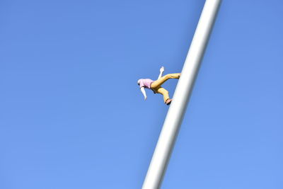 Low angle view of bird flying against clear blue sky