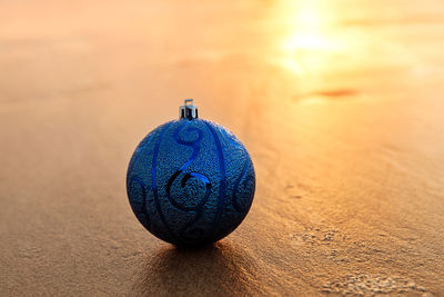 Close-up of christmas decoration on beach against blue sky