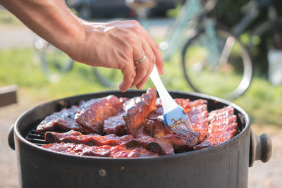 Close-up of person preparing food on barbecue grill