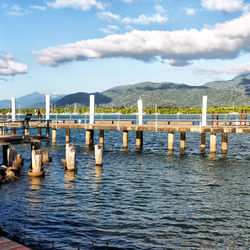 Wooden posts in lake against sky