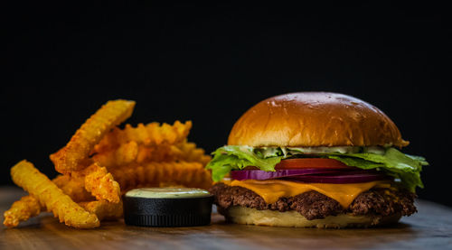 Close-up of burger on table against black background