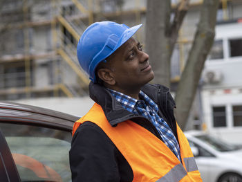 Side view of young man standing in car