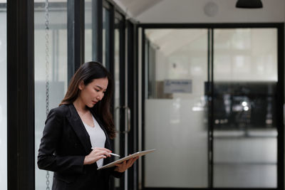 Woman looking at camera while standing in office