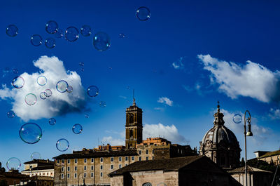 Low angle view of bubbles and buildings against sky