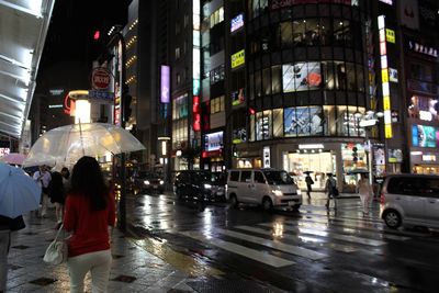 People walking on wet street in city at night