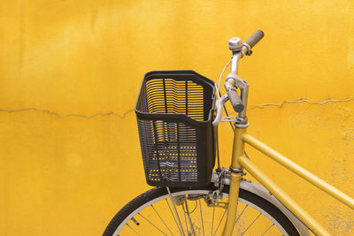 Close-up of bicycle parked against yellow wall