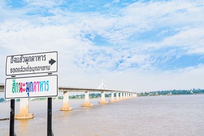 Information sign on bridge over sea against sky