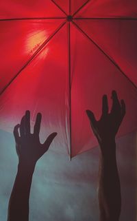 Close-up of silhouette hand against red wall