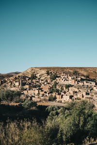 Buildings on landscape against clear blue sky