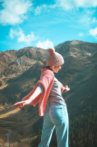 Rear view of woman looking at mountains against sky