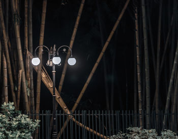 Low angle view of illuminated light against fence at night