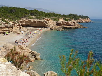 People on cliff by sea against clear sky