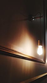 Low angle view of illuminated light bulb hanging from ceiling