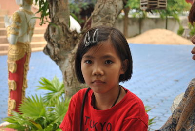 Portrait of cute girl sitting against tree