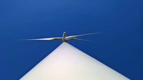 Low angle view of wind turbine against blue sky