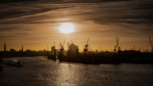 Commercial dock by sea against sky during sunset