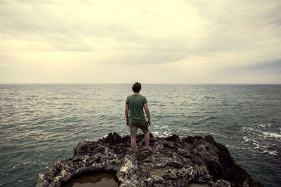 Rear view of man looking at sea against sky