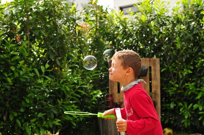 Side view of boy playing with bubbles