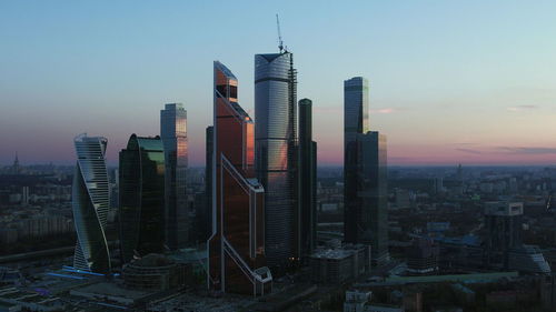 Modern buildings in city against sky during sunset