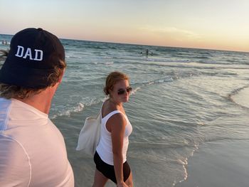 Women on beach against sky during sunset