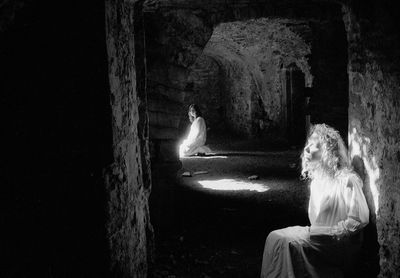 Rear view of man and woman sitting against wall at night