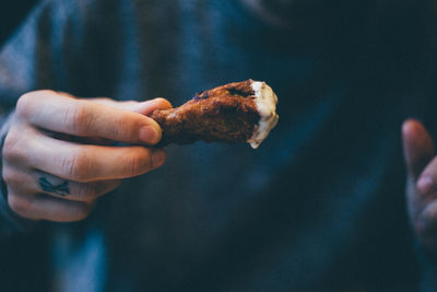 Midsection of man eating chicken meat