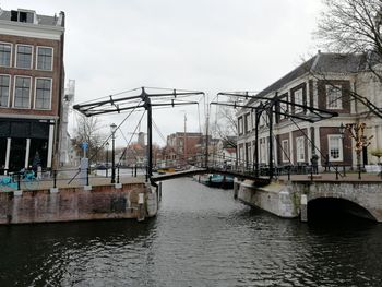 Bridge over canal amidst buildings in city against sky