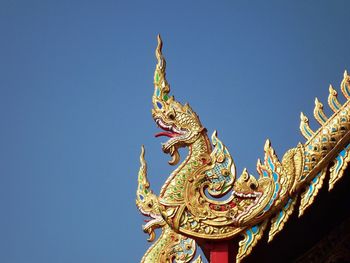 Low angle view of statue on temple against clear blue sky