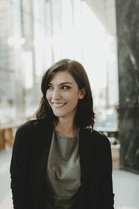 Smiling woman looking away while standing in cafe