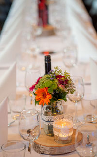 High angle view of wineglasses with flower vase arranged on table