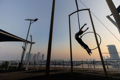 Sport exercises with aerial silk outdoor, sky background.