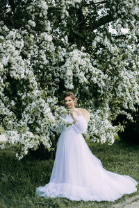 A beautiful delicate elegant woman bride in a wedding dress walks alone in a spring outdoor park