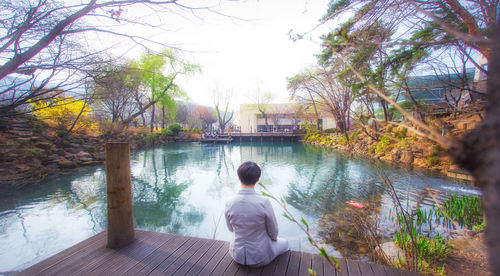 Rear view of man sitting by lake