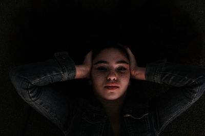 Close-up high angle view of young woman resting in darkroom