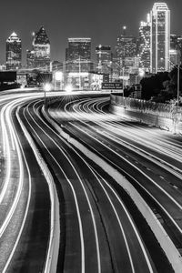 High angle view of light trails on road by buildings against sky