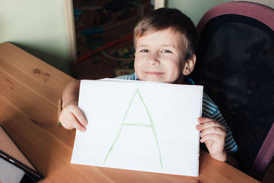 Portrait of cute boy sitting on table