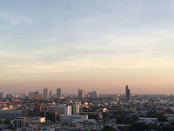 Modern buildings in city against sky during sunset