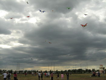 People flying over cloudy sky